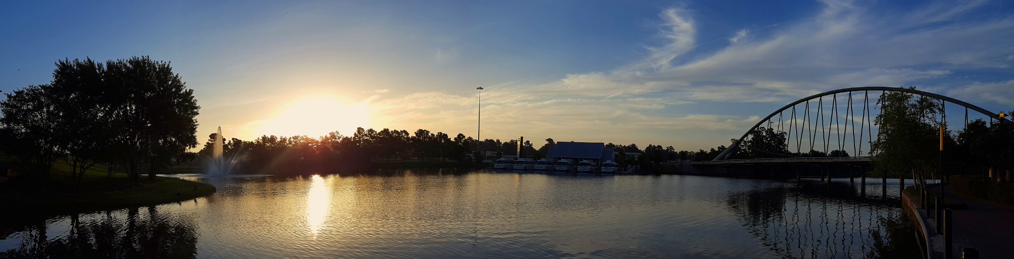 Sunset over The Woodlands lake, fountain, and arched bridge